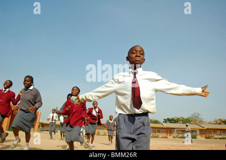 Le Nigéria, Jos, des écoliers et des écolières dans leur violet et bleu de l'uniforme scolaire, exécutant alltogether sur un champ. Banque D'Images