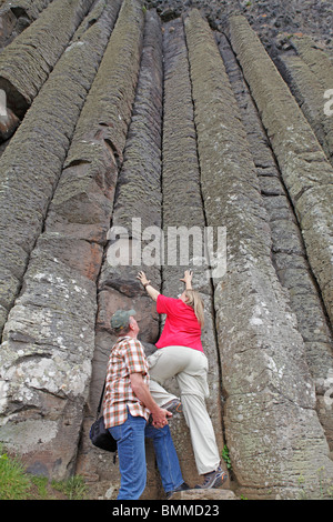 Un homme d'aider sa femme à monter les colonnes de basalte de la Chaussée des Géants, en Irlande du Nord Banque D'Images