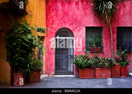 Façade d'une maison colorée à Rome (Italie), révélant une partie d'un balcon (sur la gauche) et décoré par de nombreuses plantes en pot Banque D'Images