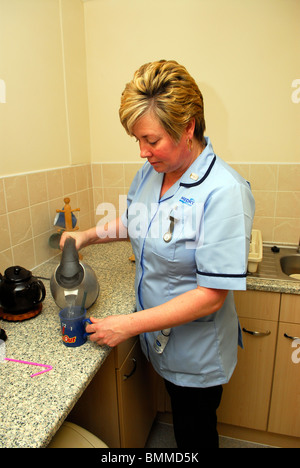 Travailleur de la santé de prendre une tasse de thé pour une personne âgée dans une maison de retraite, Wirral, UK. Banque D'Images