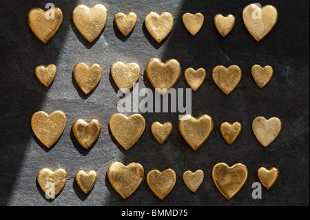 Coeur d'or contre des formes de fond d'ardoise dans l'ombre et la lumière Banque D'Images