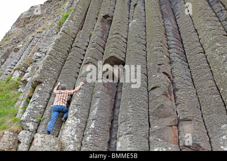 Un homme se faisant passer pour monter les colonnes de basalte de la Chaussée des Géants, en Irlande du Nord Banque D'Images