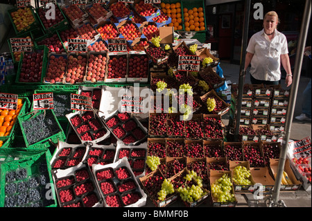 Shopping sur Oxford Street, London, UK, femme greffier la vente de fruits et légumes frais sur l'affichage Banque D'Images