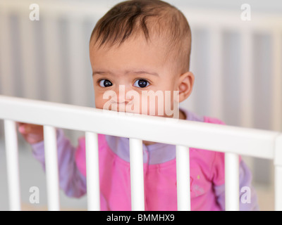 Jolie petite fille de sept mois dans un lit de bébé Banque D'Images