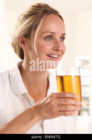 WOMAN HOLDING GLASSS DE JUS DE POMME Banque D'Images