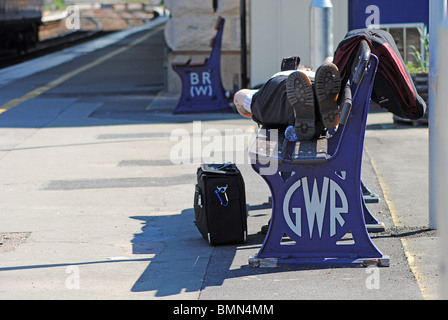 Un homme dort sur un banc à Exteter gare St Davids, UK Banque D'Images