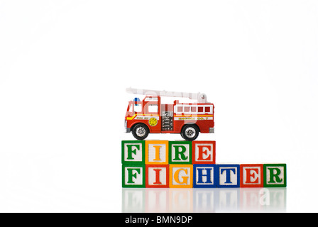 Enfants colorés blocks spelling pompier avec un jouet Camion à incendie Banque D'Images