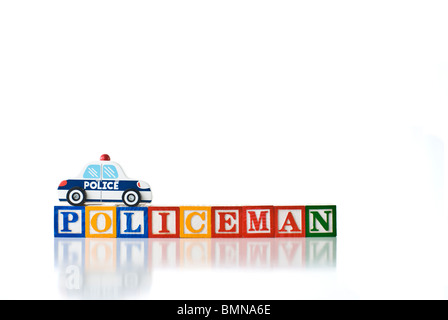 Enfants colorés blocks spelling POLICKEMAN avec un jouet voiture de police Banque D'Images