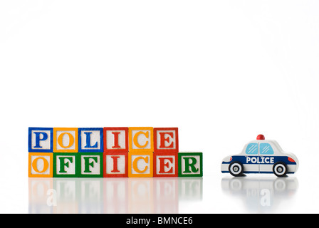 Enfants colorés blocks spelling AGENT DE POLICE avec un jouet voiture de police Banque D'Images