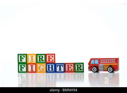 Enfants colorés blocks spelling pompier avec un jouet Camion à incendie Banque D'Images