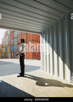 Portrait of Mid adult businessman standing près de conteneur et de parler . La forme verticale, side view, copy space Banque D'Images
