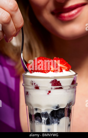 Close-up of woman eating un parfait au yogourt et aux petits fruits mélangés -- l'accent sur le dessert Banque D'Images