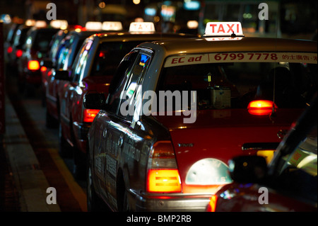 Les taxis, la queue dans une file d'attente de clients pendant la nuit, avec les feux allumés. Banque D'Images