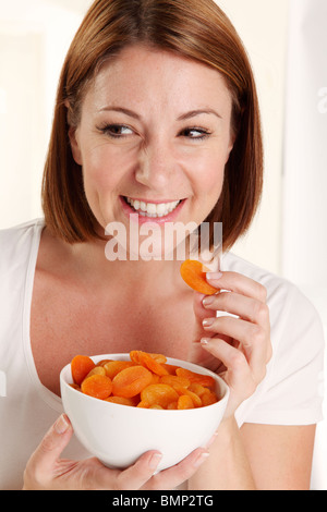 WOMAN EATING abricots séchés Banque D'Images