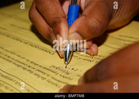 L'université et de l'examen le remplissage de formulaire avec main droite par une petite fille avec son stylo à bille bleu Banque D'Images