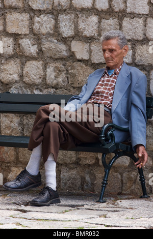 Vieil homme assis pensivement sur le banc et le tabagisme, Dubrovnik, Dalmatie, Croatie Banque D'Images