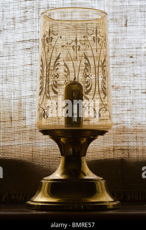 Vieille lampe bougie sur windowboard contre fenêtre couverte de Hesse Banque D'Images