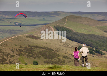 UK, Derbyshire, Mam Tor, couple watching parapente survolant Hollin's Cross Banque D'Images