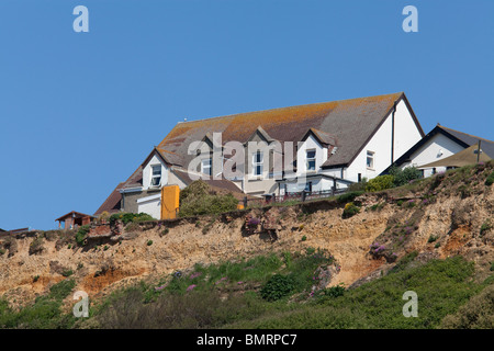 Bâtiments sur le bord de la falaise à Barton sur Mer à Hampshire en danger de tomber dans la mer en raison de l'érosion côtière Banque D'Images