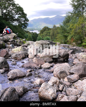 Un cycliste se reposant à Ashness Pont dans le parc national de Lake District en Cumbrie, donnant sur Derwent water avec Skiddau derrière Banque D'Images