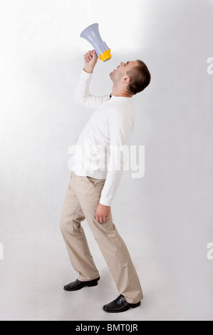 Jeune homme tenant un mégaphone et crier Banque D'Images