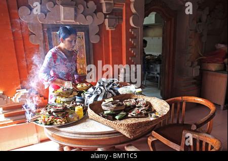 Dame balinais la préparation des offrandes à être mis sur des sanctuaires. Il y a encens brûlant sur le plateau d'Ubud, Bali, Indonésie Banque D'Images