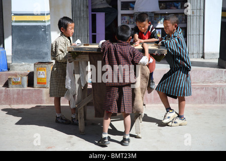 Un groupe de quatre jeunes garçons jouent avec le populaire jeu de société locale dans la rue Carrom Paro, Bhoutan. Banque D'Images