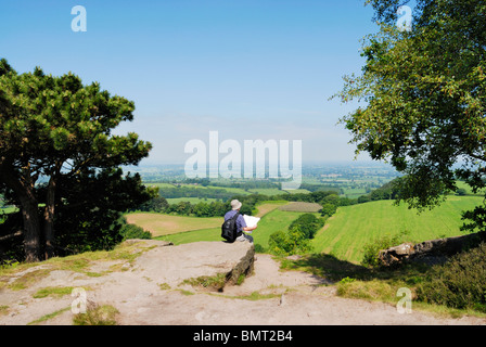 Walker avec la carte d'admirer la vue sur la Plaine du Cheshire du sentier de grès. Banque D'Images