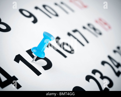 Un bouton poussoir bleu sur le 15e jour d'un calendrier. Banque D'Images