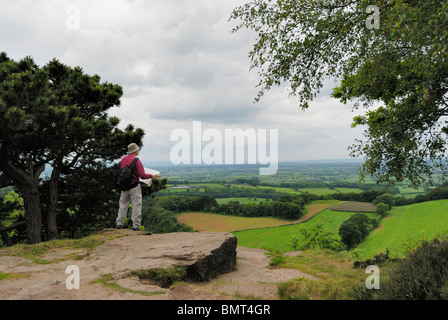 Walker avec la carte d'admirer la vue sur la Plaine du Cheshire du sentier de grès. Banque D'Images