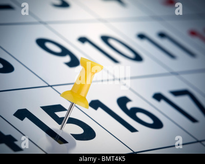 Un bouton poussoir jaune sur le 15e jour d'un calendrier. Banque D'Images