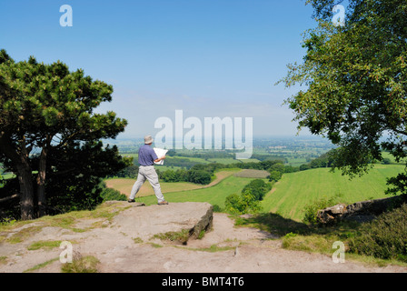 Walker avec la carte d'admirer la vue sur la Plaine du Cheshire du sentier de grès. Banque D'Images