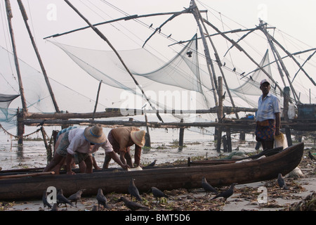 Les Pêcheurs avec leur bateau près de filets de pêche chinois au fort Kochi (Cochin) plage au Kerala, en Inde. Banque D'Images