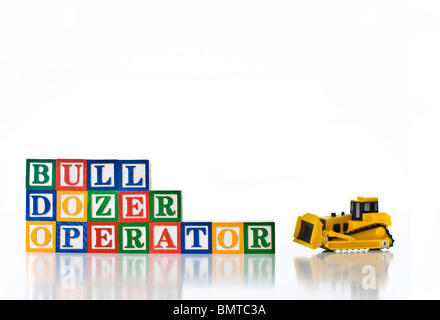 Enfants colorés blocks spelling Bull Dozer opérateur à l'aide d'un bulldozer modèle Banque D'Images