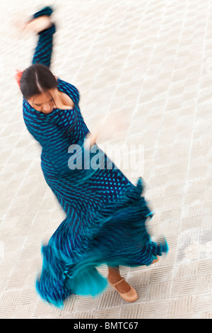 Une motion blurred vitesse d'obturation lente tourné d'une femme espagnole traditionnelle danse danseuse de flamenco dans une robe à pois bleu Banque D'Images