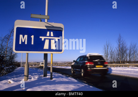 Une voiture passe roadsign affirmant début de l'autoroute M1 dans la neige de l'hiver près de Leeds Yorkshire UK Banque D'Images