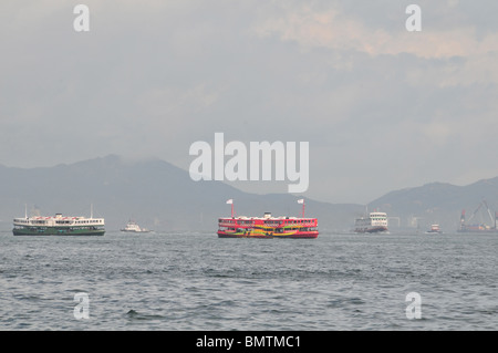 Profil de la Croix de Victoria Harbour, centré sur le rouge et vert Star Ferries traversant du centre de Kowloon, Hong Kong Banque D'Images