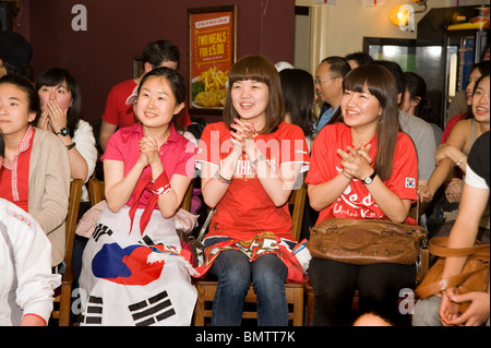 Les jeunes femmes sud-coréen football supporters amplexicaule leurs mains tout en regardant leur équipe de la Coupe du Monde 2010 dans un pub de Londres, nouveau Banque D'Images