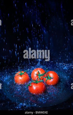 Les tomates fraîches sous le robinet avec de l'eau gouttes Banque D'Images