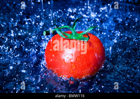 La tomate fraîche sous le robinet avec de l'eau gouttes Banque D'Images