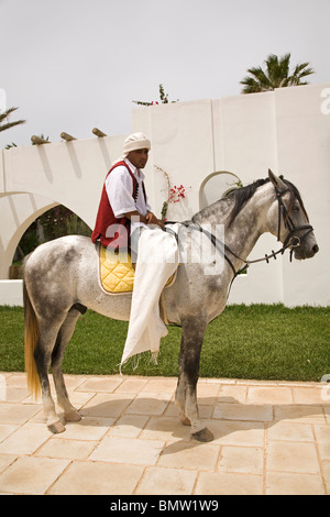 Un homme tunisien à califourchon sur un cheval gris pommelé à Djerba (Tunisie). Banque D'Images