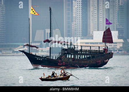 Dans le port de Victoria, une jonque classic sails en face de l'horizon de Hong Kong et les gratte-ciel que la ligne de cette ville historique. Banque D'Images