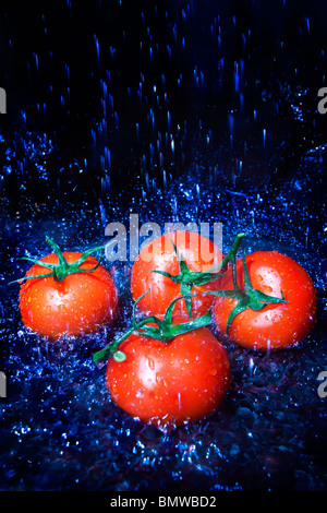 Les tomates fraîches sous le robinet avec de l'eau gouttes Banque D'Images