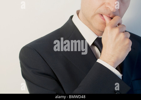 Homme portant un costume bleu, mordre son pouce. Visage et des épaules. Voir de très près. Banque D'Images