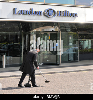 West End de Londres Mayfair Park Lane Hilton Hotel sign close up entrée principale avant & canopy portier en uniforme nettoyage de la route approche panoramique England UK Banque D'Images