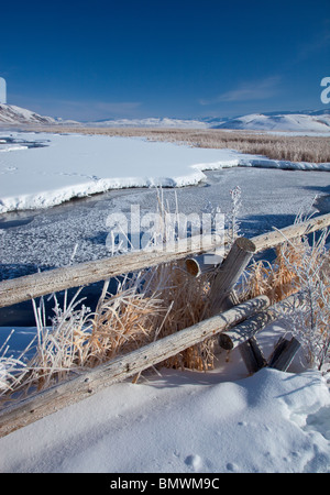 Jackson Hole, Wyoming : l'hiver la lumière du matin sur la ligne de clôture dépoli au-dessus d'un plat congelé Creek dans le National Elk Refuge Banque D'Images