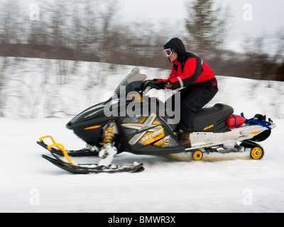 Un jeune homme conduit une motoneige à travers la neige à Kiruna, en Laponie, le nord de la Suède. Banque D'Images
