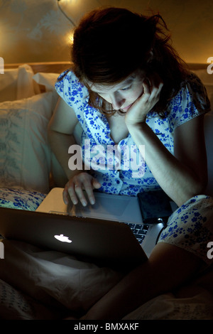 Femme au lit, tard dans la nuit sur l'ordinateur portable Banque D'Images