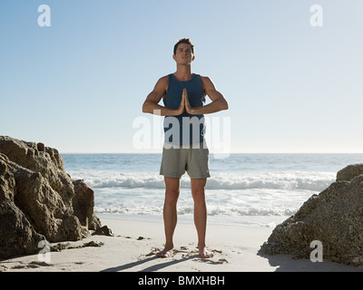 Jeune homme faisant du yoga on beach Banque D'Images