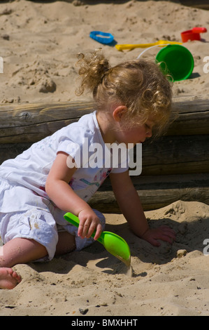 2 ans, fille, jouant dans un bac à sable avec une pelle en plastique Banque D'Images